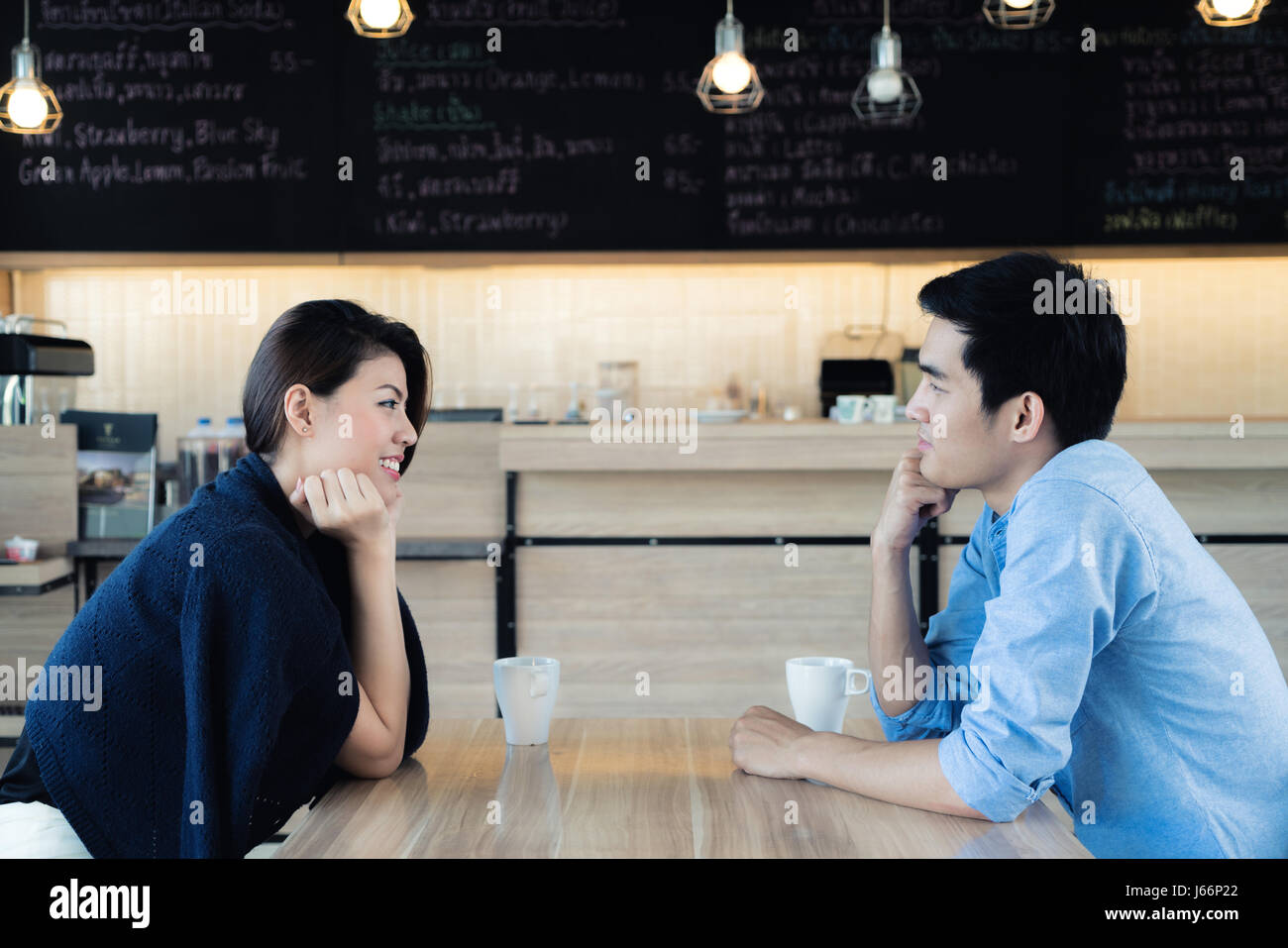 Dating in a cafe. Beautiful Asian lover couple sitting in a cafe enjoying in coffee and conversation. Love and romance. Stock Photo
