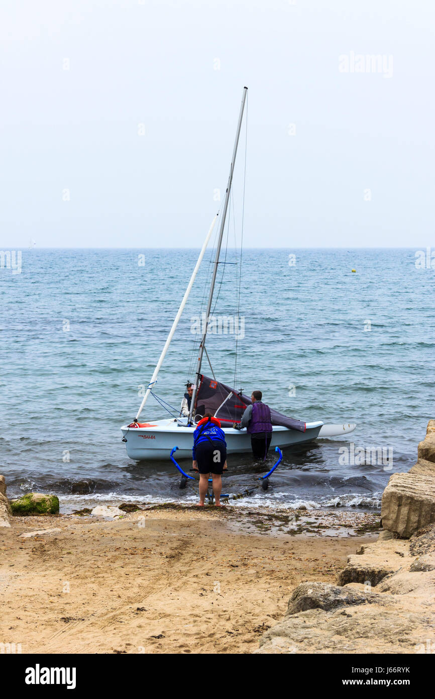 Two people launching a sailing dinghy from the slipway at Bowleaze Cove