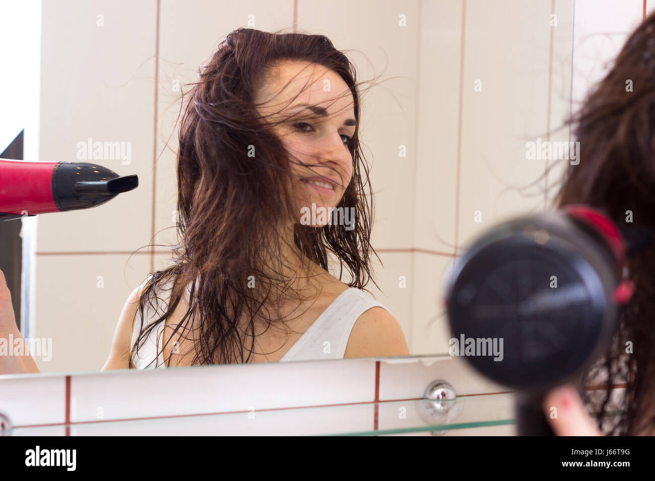 Young woman drying her hair in bathroom Stock Photo - Alamy
