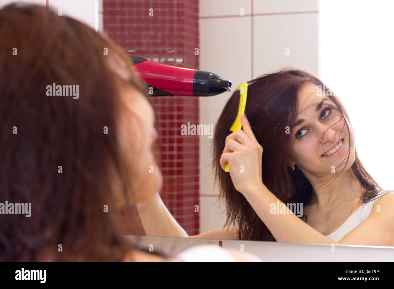 Young woman drying her hair in bathroom Stock Photo - Alamy