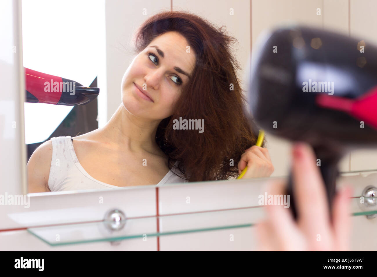 Young woman drying her hair in bathroom Stock Photo - Alamy