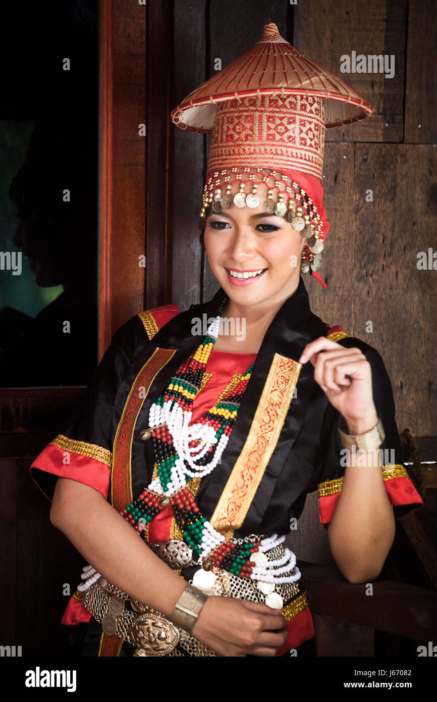 Beautiful young Bidayu woman in traditional ethnic costume of the Dayak ethnic group. Posing for the camera with big colorful headdress in Borneo Stock Photo