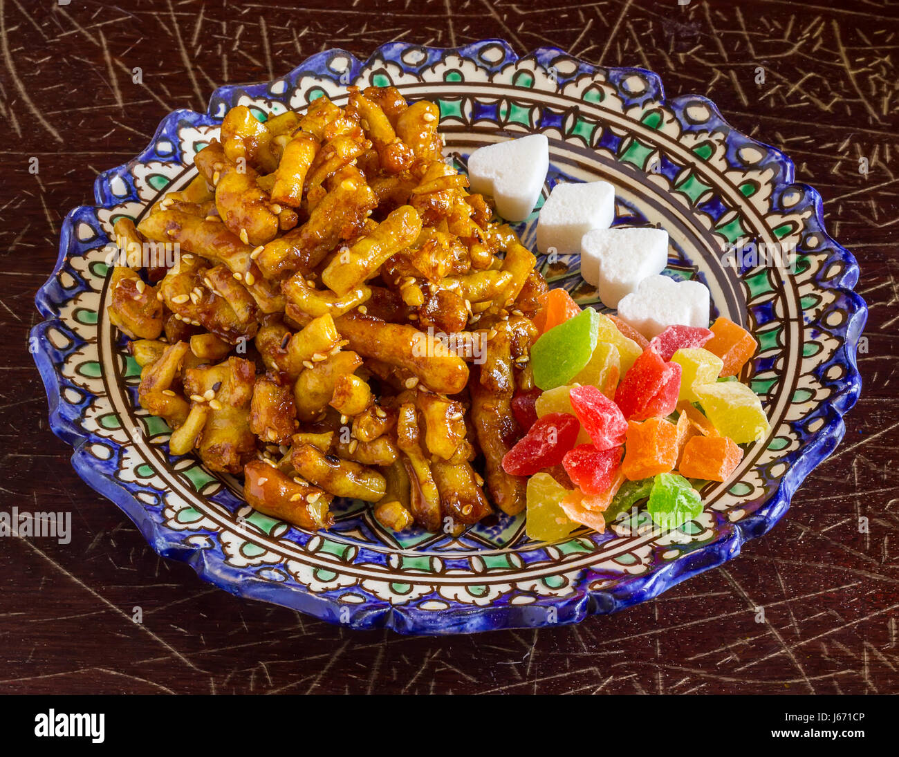 Chak-chak oriental sweets, dried fruit and figured sugar in a traditional oriental plate on an old cracked varnished surface Stock Photo