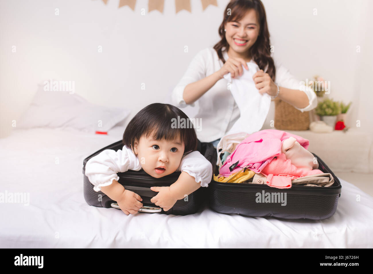 Asian mom and baby girl with suitcase baggage and clothes ready for