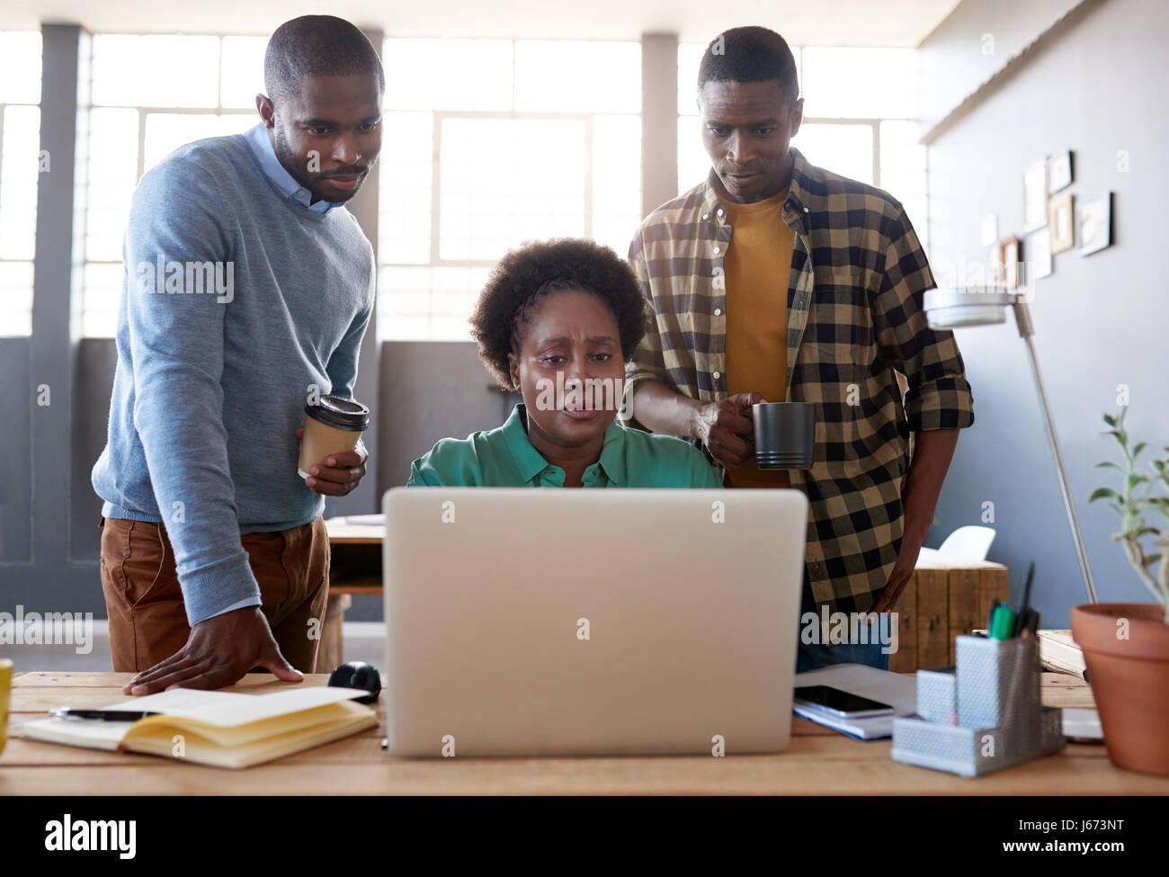 Focused young African coworkers using a laptop in an office Stock Photo ...