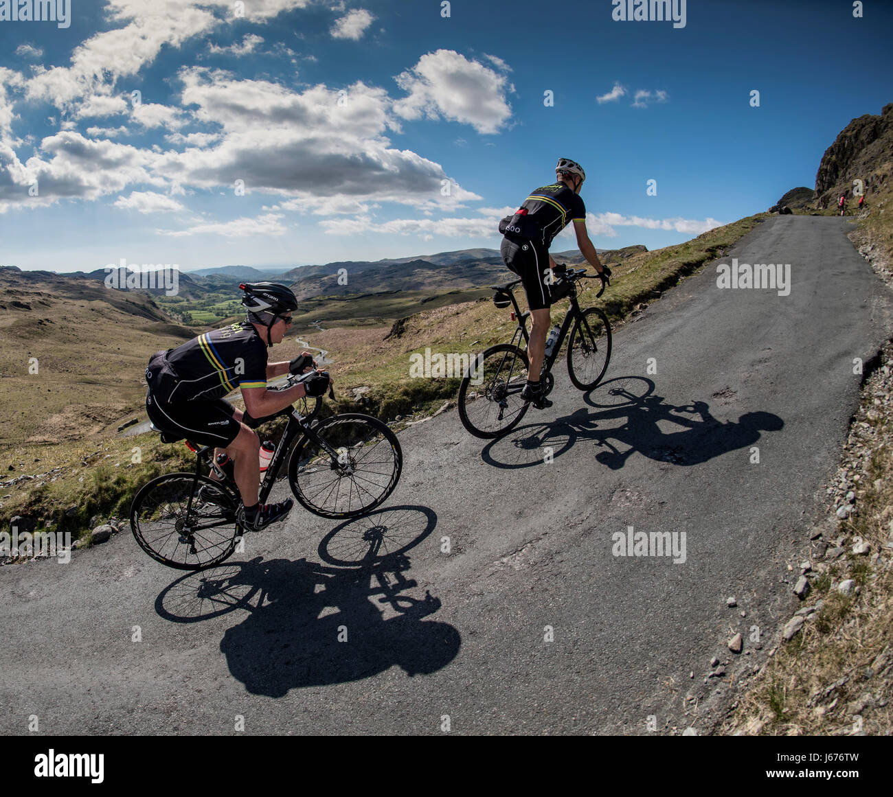 Two cyclists climbing Hardknott Pass, Cumbria, UK. Stock Photo
