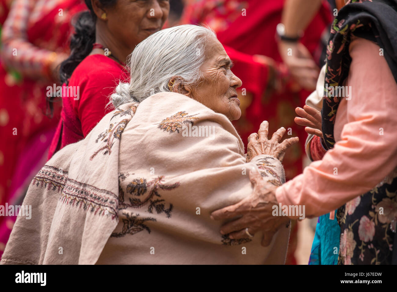 Kathmandu, Nepal - Apr 15, 2016: Elderly ladies in traditional Nepalese clothing watching a passing ceremony procession. Stock Photo