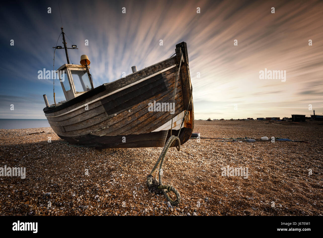 Single abandoned old fishing boat on a pebble beach with long exposure ...