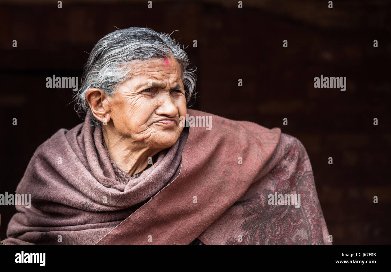 Kathmandu, Nepal - Apr 15, 2016: Elderly ladies in traditional Nepalese clothing watching a passing ceremony procession. Stock Photo
