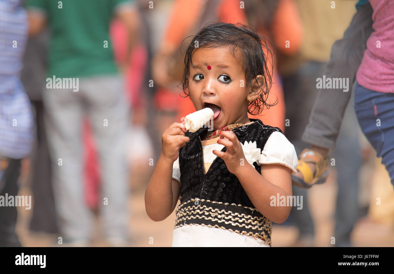 Kathmandu, Nepal - Apr 15, 2017: Little girl eagerly eating an ice cream lolly. Stock Photo