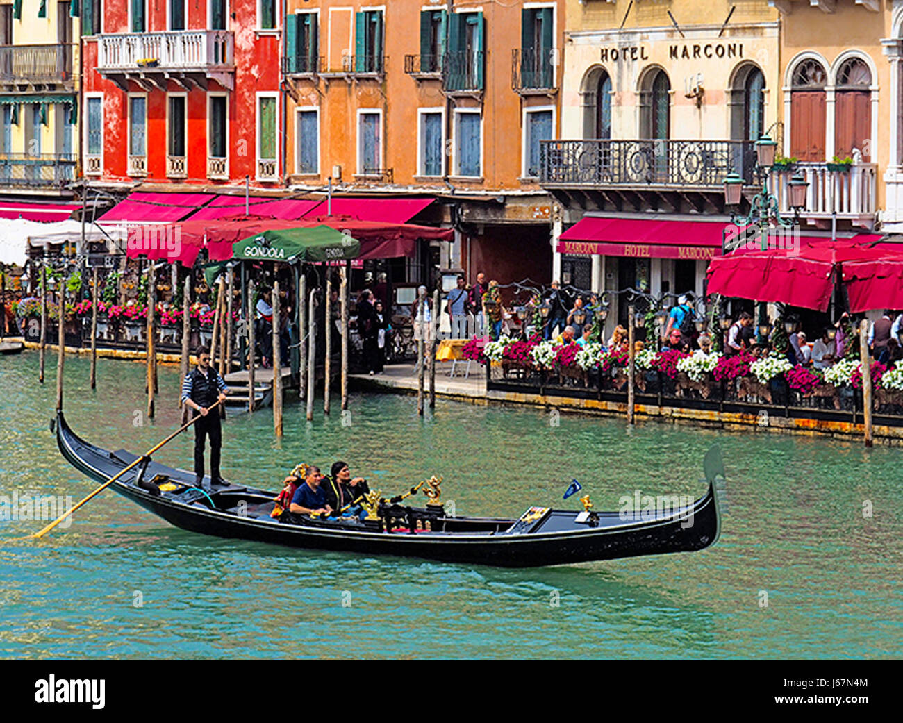 Gondola passing restaurants and hotels on the Grand Canal near Rialto Bridge in Venice. Stock Photo