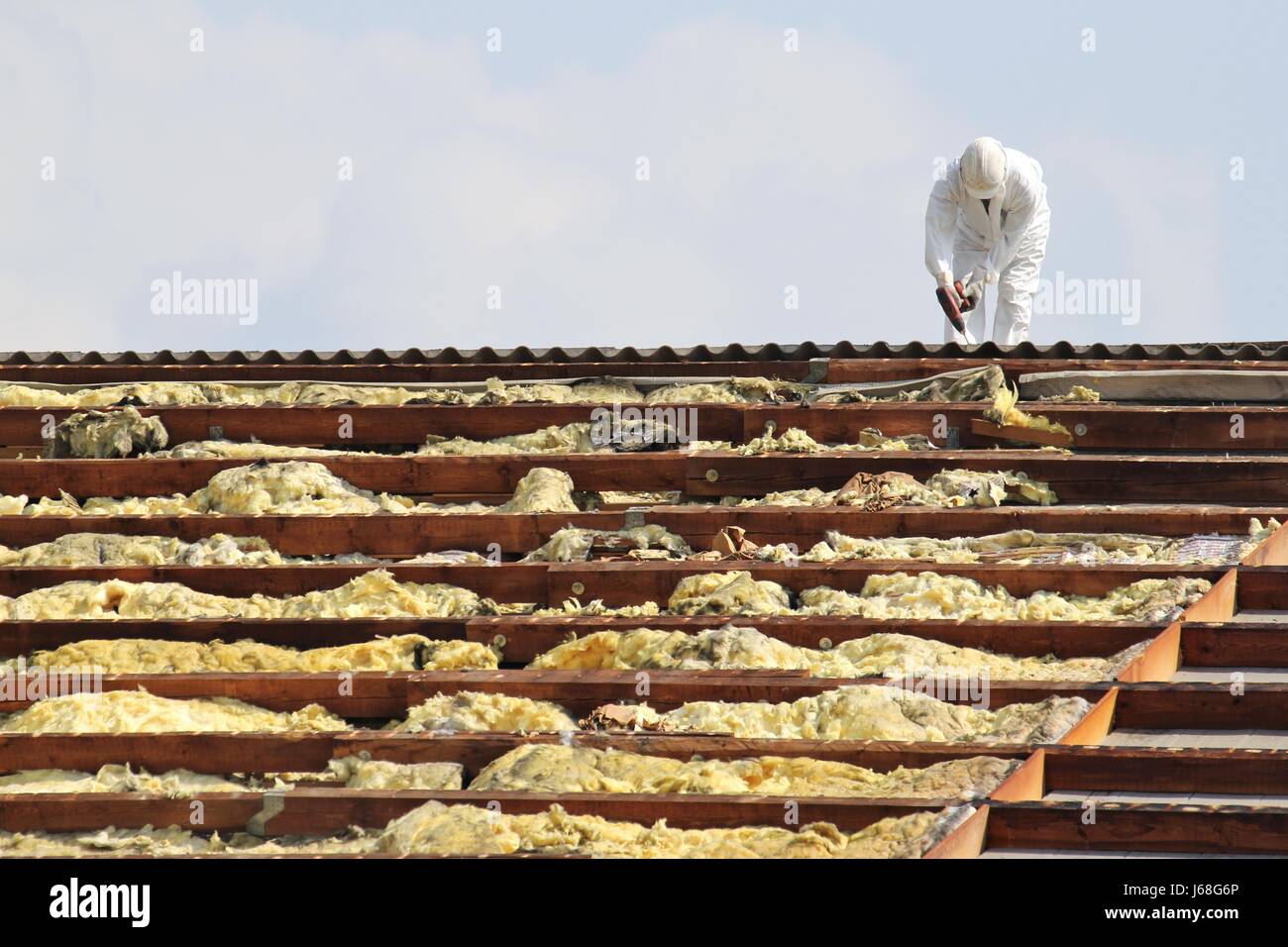 workman at rooftop of building being remediated Stock Photo