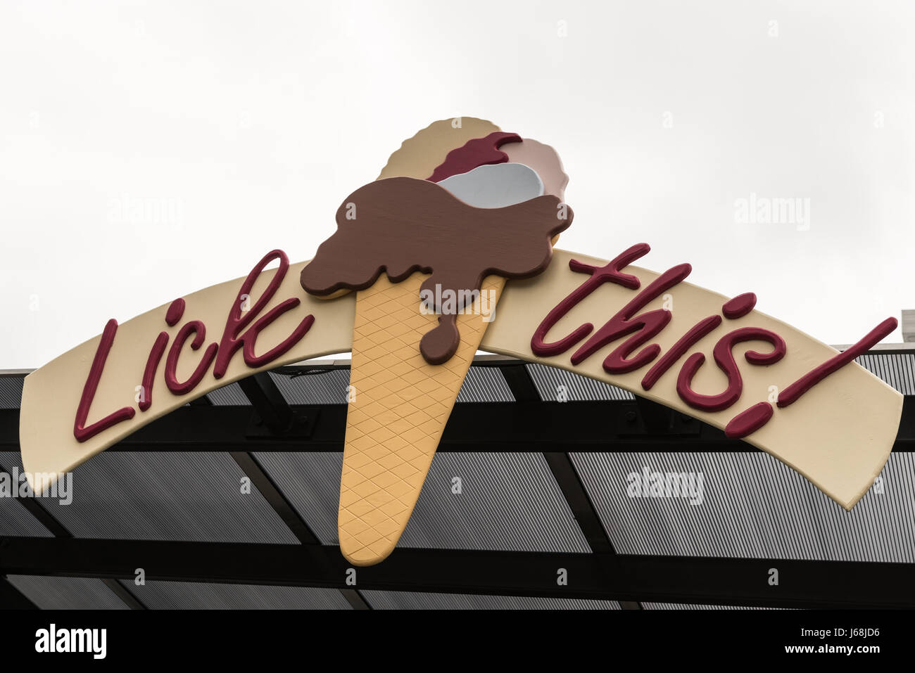 Napier, New Zealand - March 9, 2017: Lick this slogan on billboard with ice cream cone under silver sky and fixed on a roof. Stock Photo