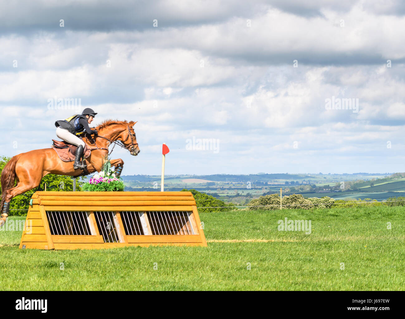 Rockingham Castle grounds, Corby, England. Saturday 20th May 2017. Elphege Copet-Dortet and her horse Ulahupbiats leap an obstacle with the Welland valley in the background during the cross country phase of the Rockingham International Horse Trials on Saturday 20th May 2017 in the grounds of the norman Rockingham castle at Corby, England. Credit: miscellany/Alamy Live News Stock Photo