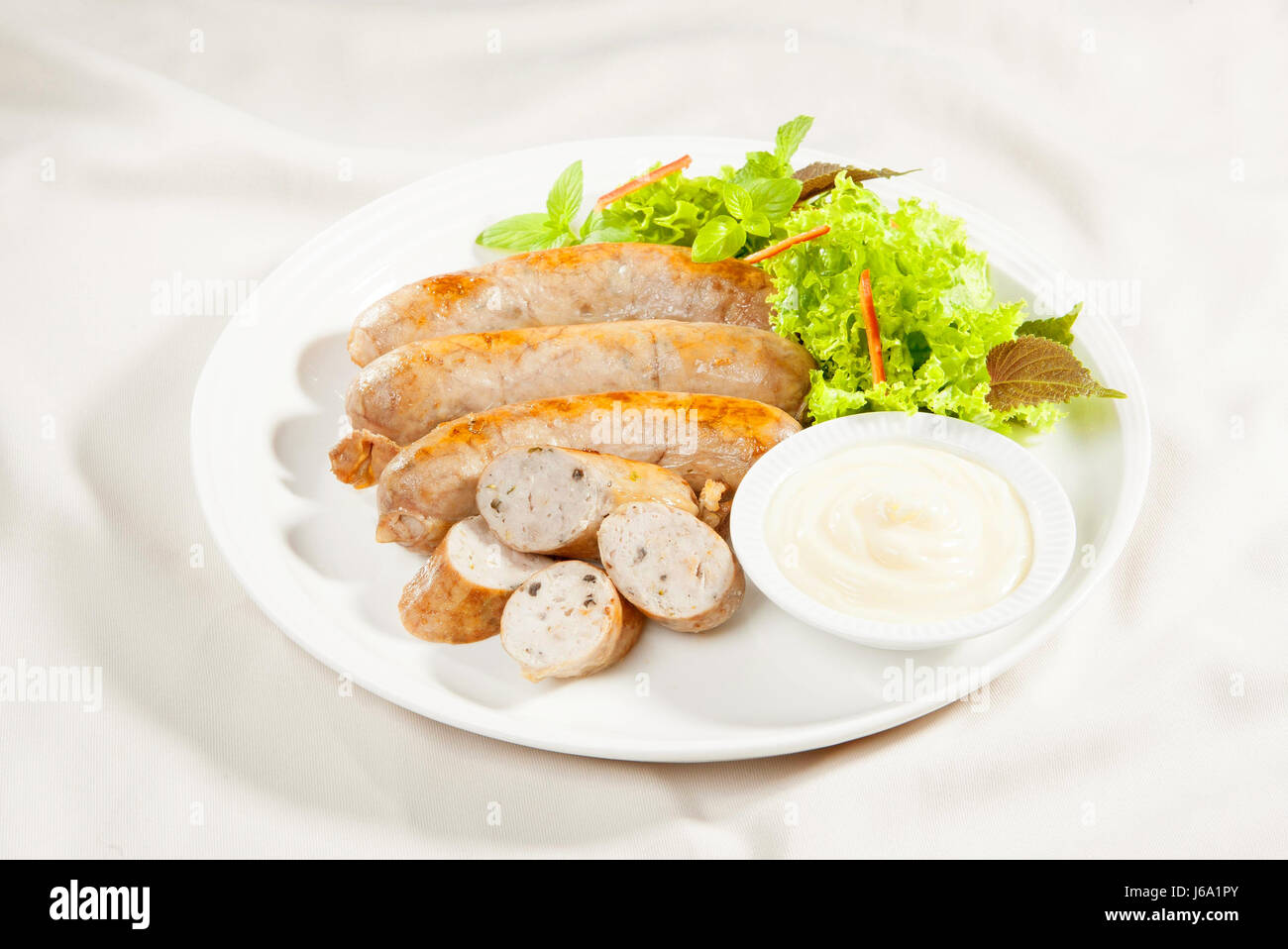Frog saussages with lettuce, herbs and sauce on white background Stock Photo