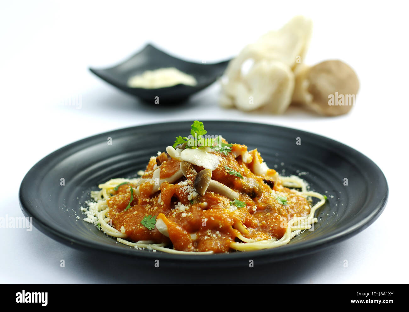 Sauteed mushroom with tomatoes sauce and ramen noodle on black dish