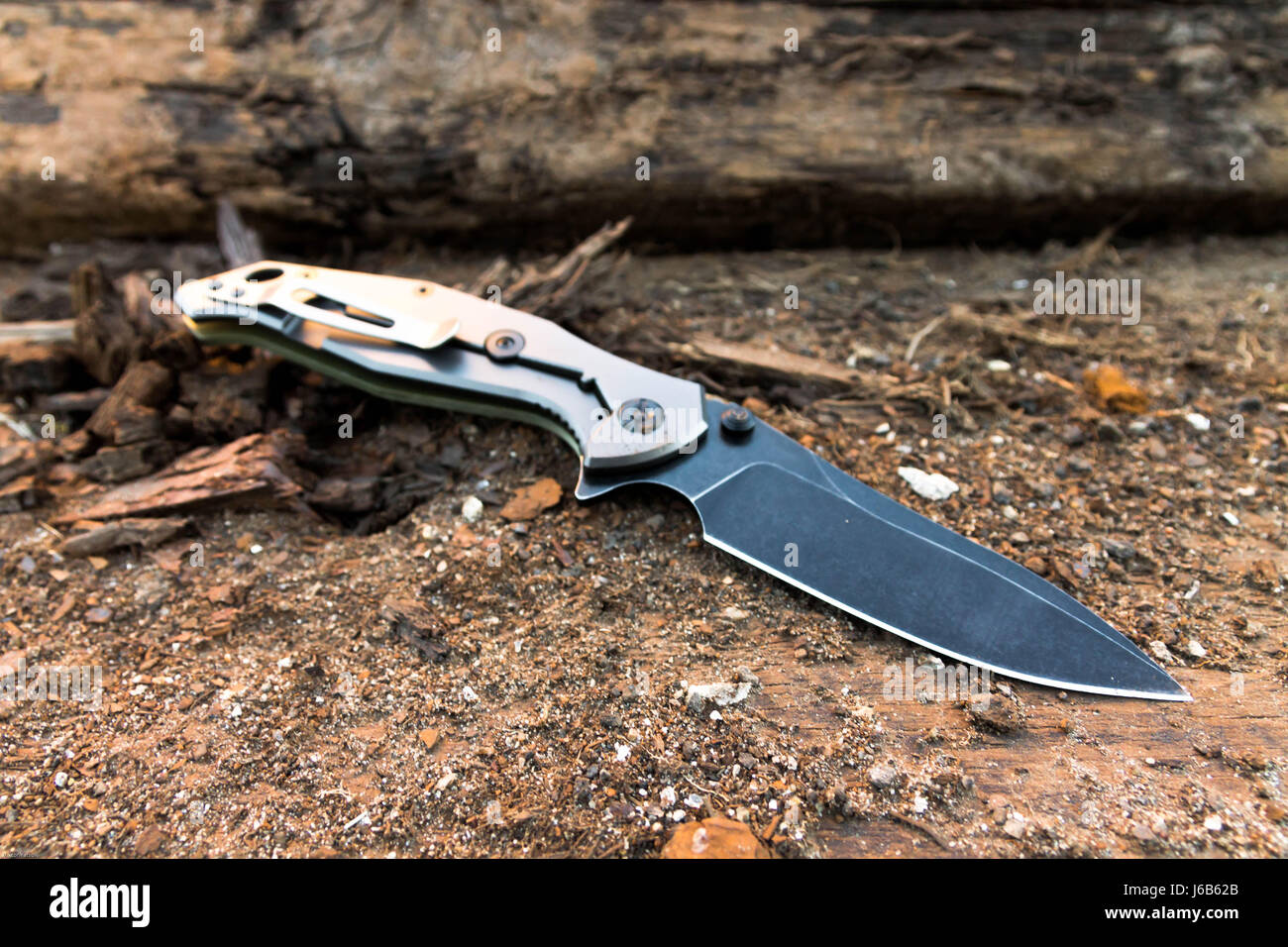 Tactical knife with a black blade on a background of brown wood. Stock Photo