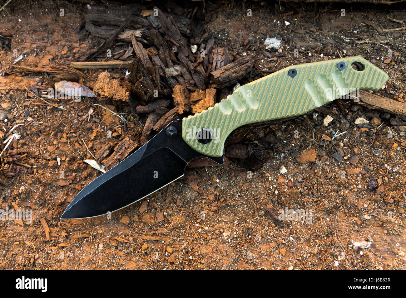 Knife with black blade and green handl. Old wood. Stock Photo