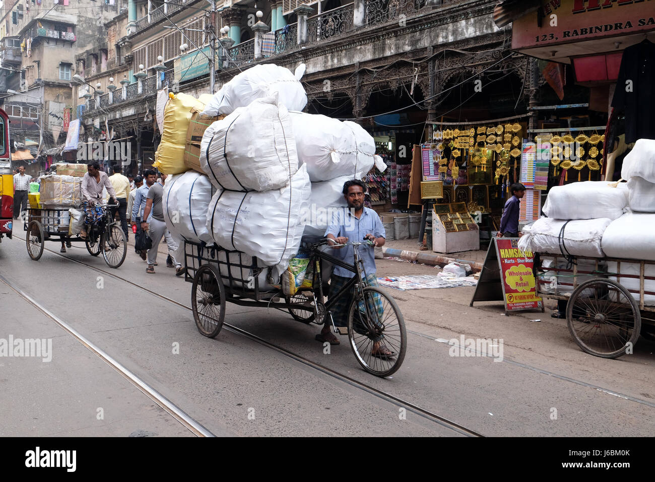 Worker pulling bale on tricycle rickshaw along a busy street in Kolkata, India on February 11, 2016. Stock Photo