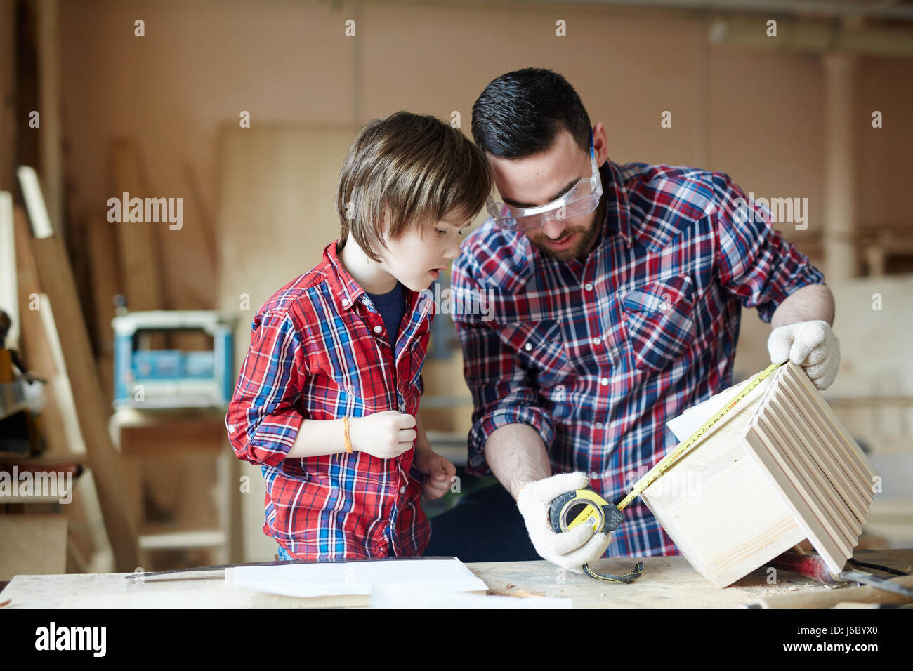 Man and little boy measuring height of starling-house Stock Photo