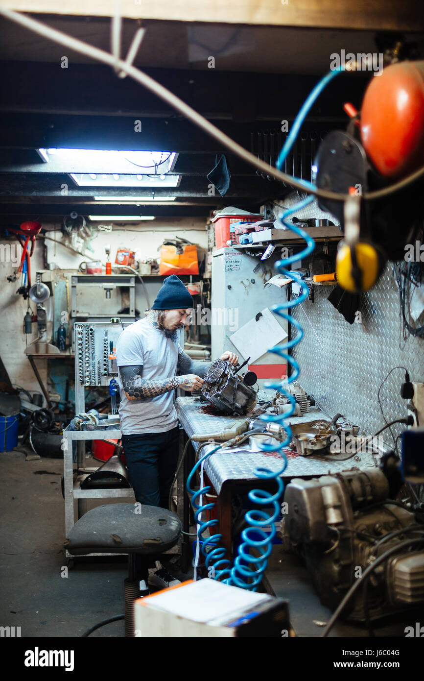 Hipster repairing engine of motor-bike Stock Photo - Alamy
