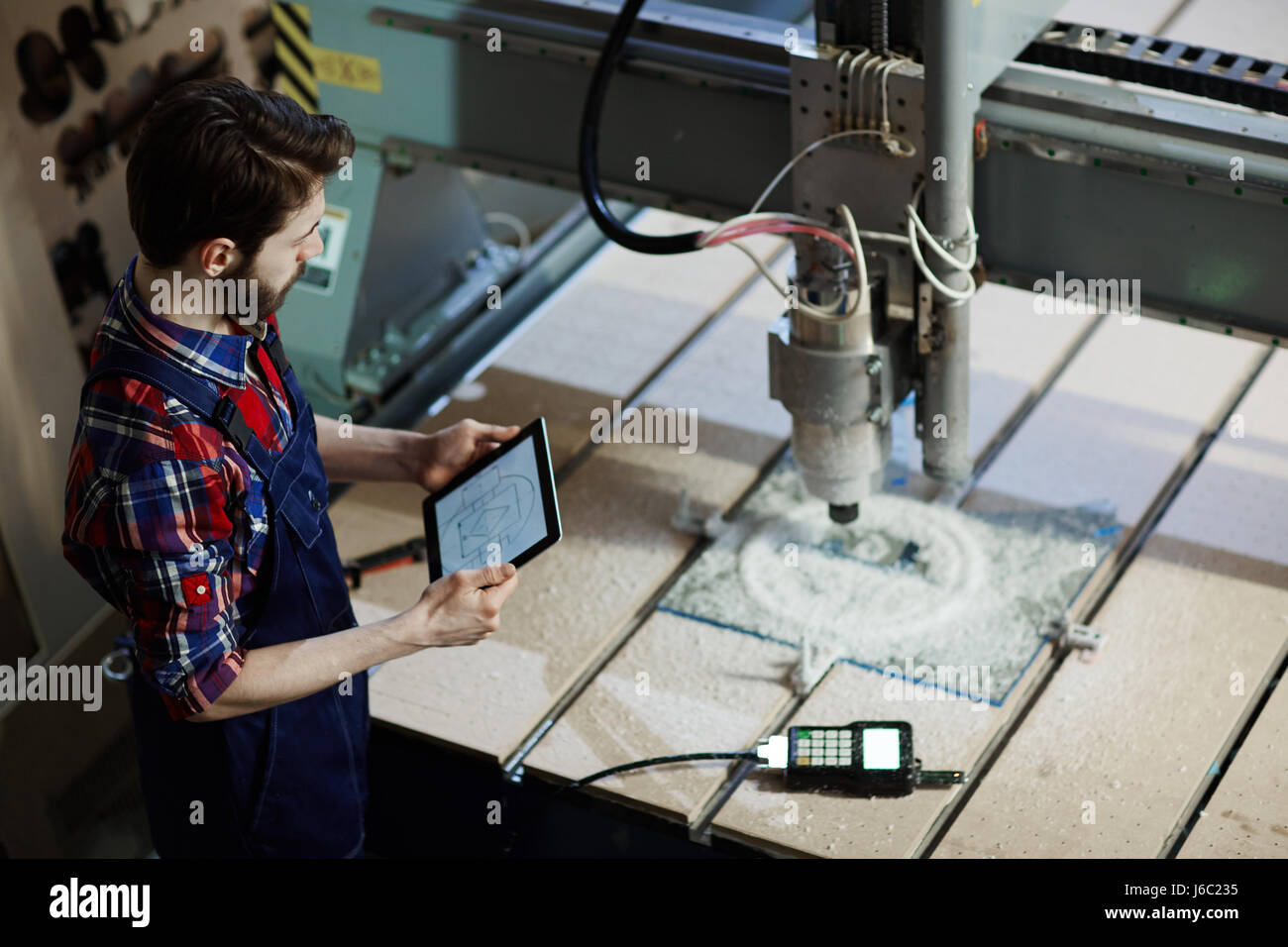 Factory worker operating cutter machine using digital tablet in workshop Stock Photo