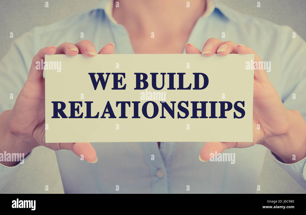Closeup business woman hands holding white card sign with we build ...