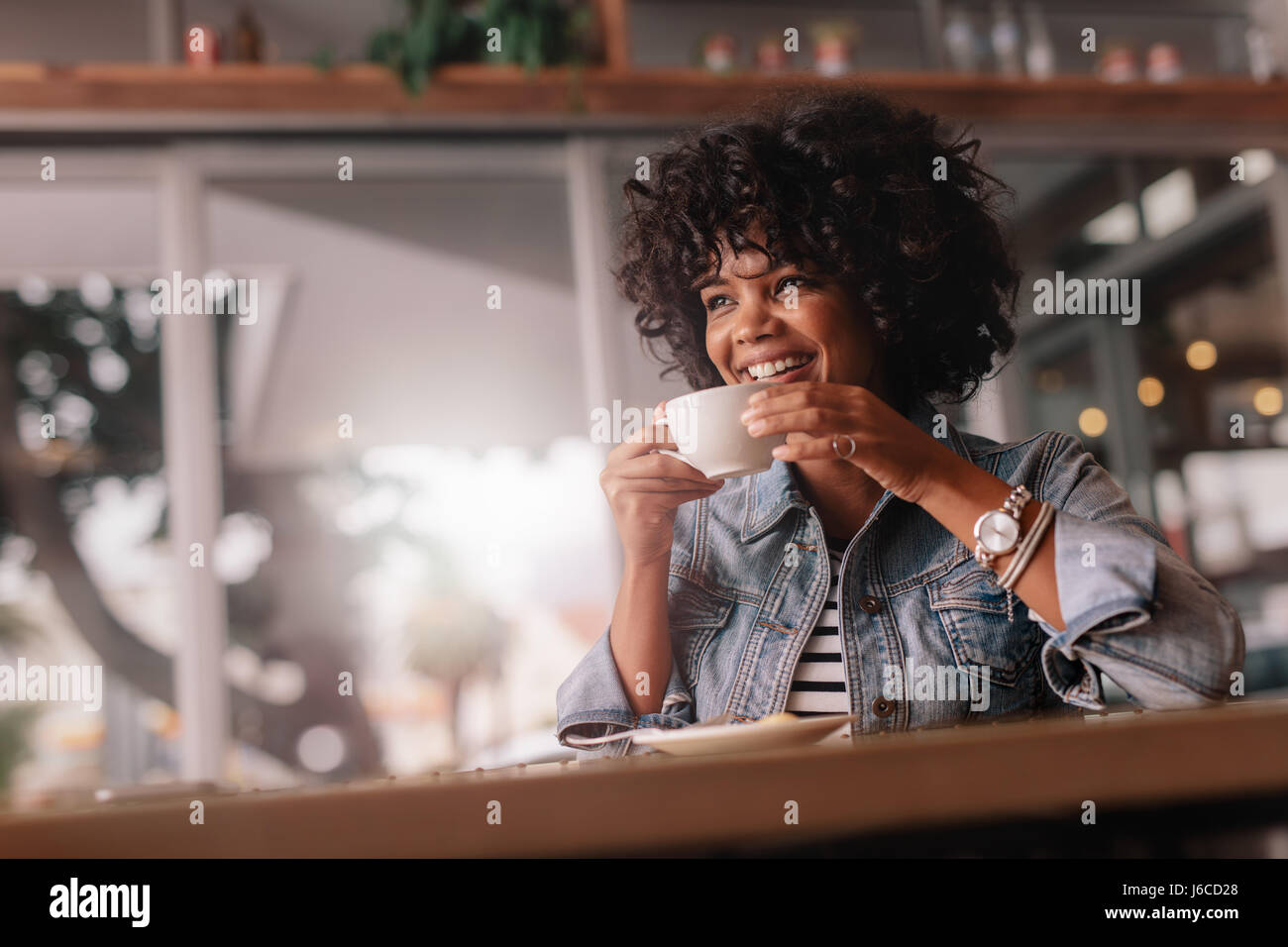 Portrait of beautiful young african woman sitting in a cafe and ...