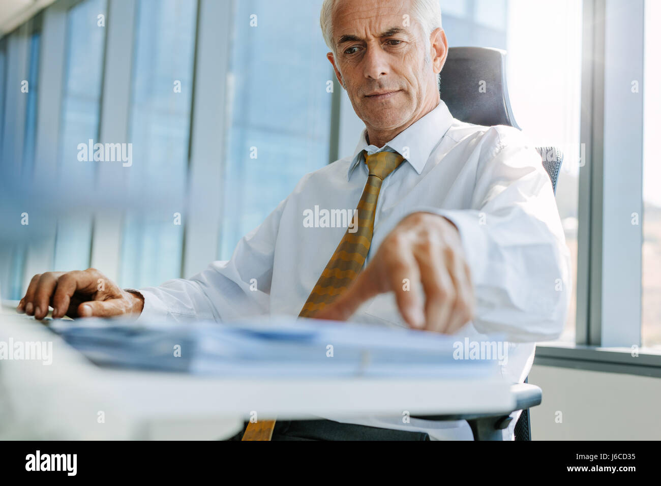 Shot of mature businessman sitting at his desk and working. Senior male entrepreneur in his office. Stock Photo