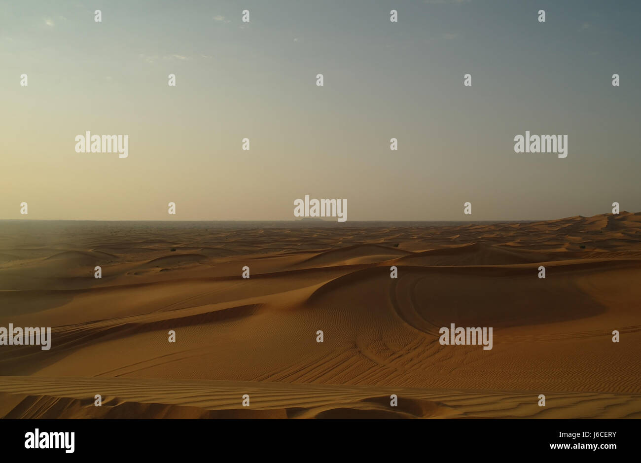Blue sky evening sunlight view across orange sand dunes desert landscape to level horizon, Alpha Tours Desert Safari, Dubai, United Arab Emirates Stock Photo