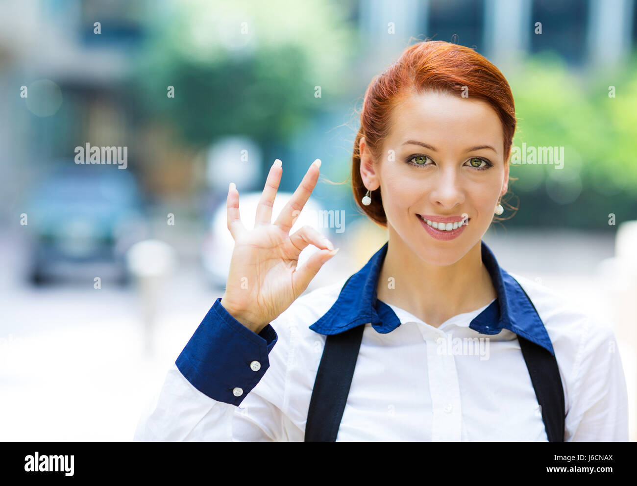 Closeup portrait happy smiling business woman, customer, professional giving ok sign isolated background outdoors corporate office. Positive human emo Stock Photo
