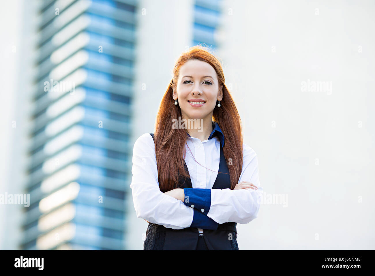 Closeup portrait young, attractive, confident business woman, company executive employee standing with arms crossed isolated in front of corporate off Stock Photo
