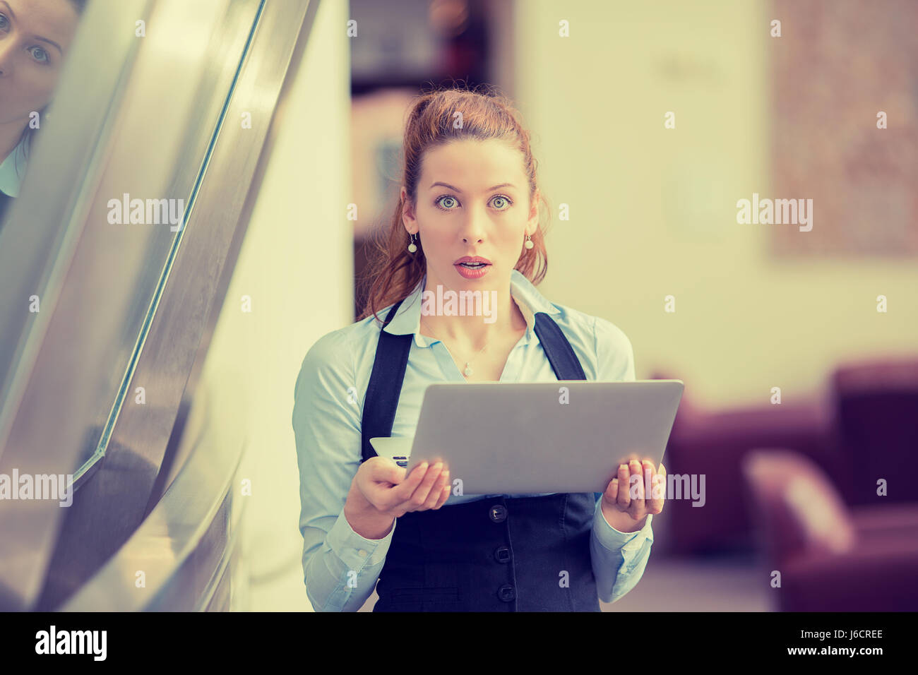 Portrait anxious young girl looking at camera seeing bad news or photos on computer, disgusting shocked emotion on her face isolated office windows ba Stock Photo