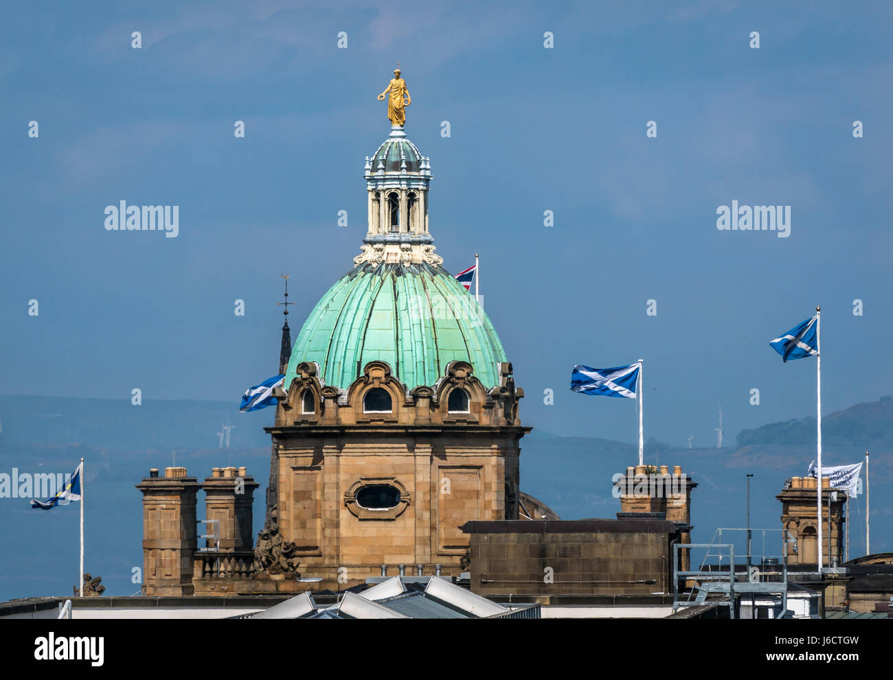 View of copper dome and spire on top of Bank of Scotland headquarters, The Mound, Edinburgh, Scotland Uk, with waving saltire St Andrews Cross flags Stock Photo