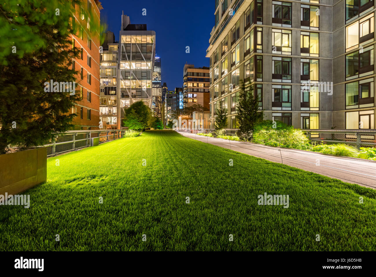 Highline promenade and lawn at twilight with city lights in the heart of Chelsea. Manhattan, New York City Stock Photo