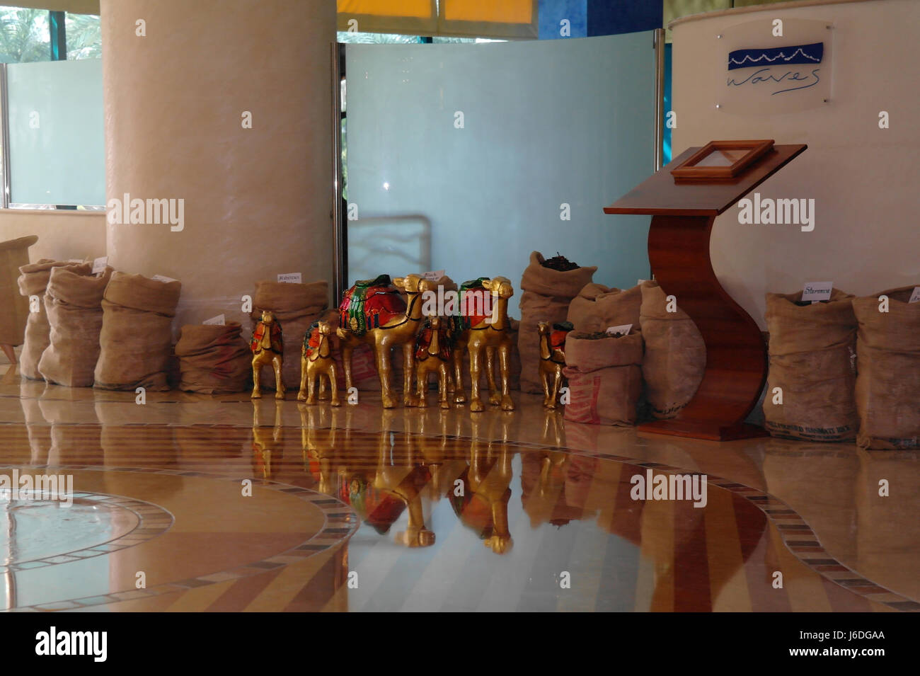 Six gold camel images in front of spice sacks reflecting glossy tiles floor, Waves Restaurant, Le Meridien Hotel, Mina Seyahi Beach Resort, Dubai, UAE Stock Photo
