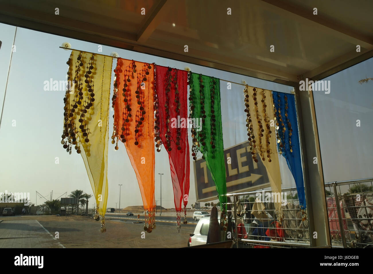 Interior view through head-scarfs window of shop selling tourist Arab clothes, looking east over parking lot, Al Badayer, Dubai-Hatta Road, Dubai, UAE Stock Photo