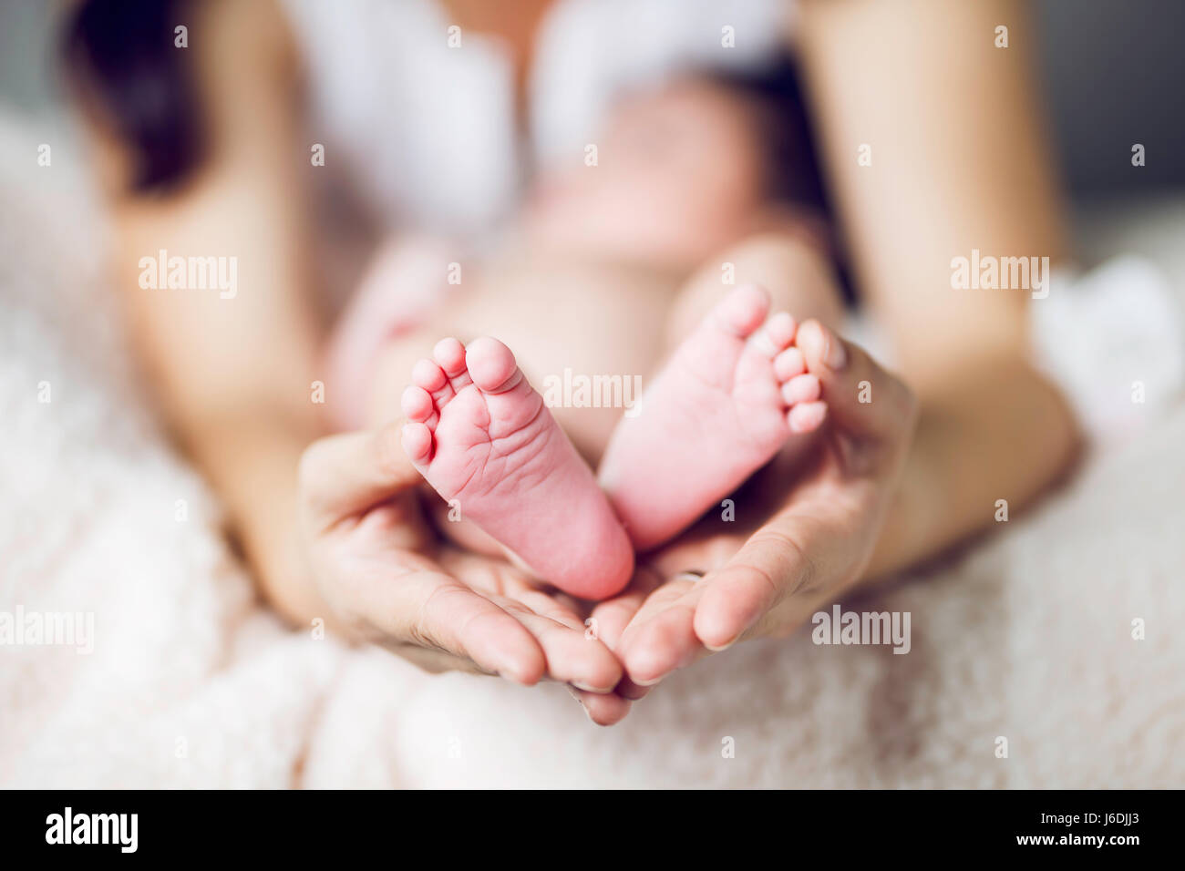 Lovely baby feet in her mum hands Stock Photo