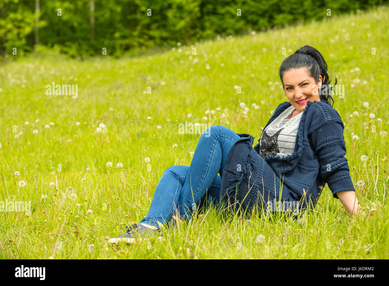 Attractive woman sitting on green grass in nature Stock Photo - Alamy