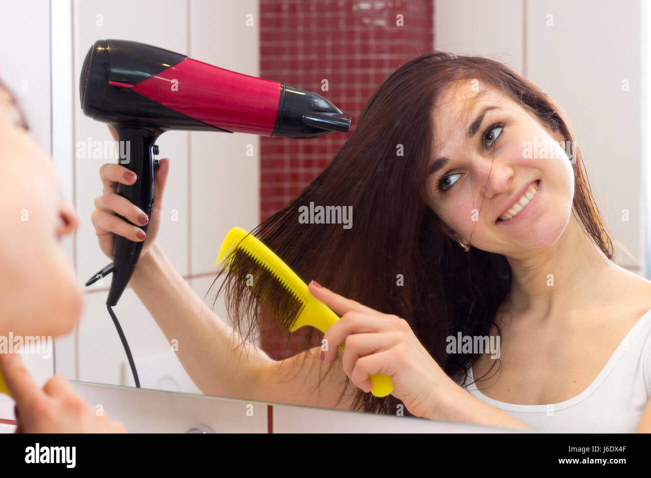 Young woman drying her hair in bathroom Stock Photo - Alamy