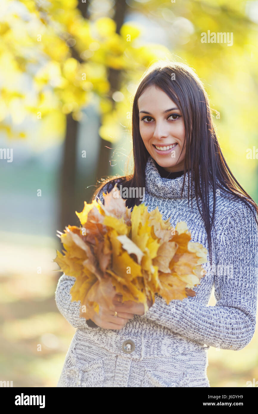 Happy smiling young woman holding maple leaves Stock Photo - Alamy