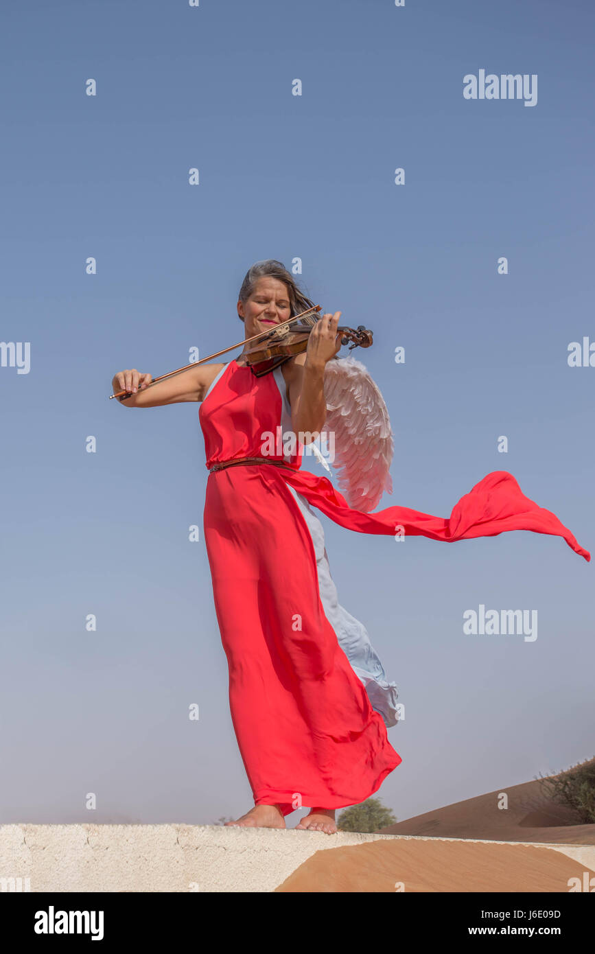 Angel playing violin in the desert Stock Photo