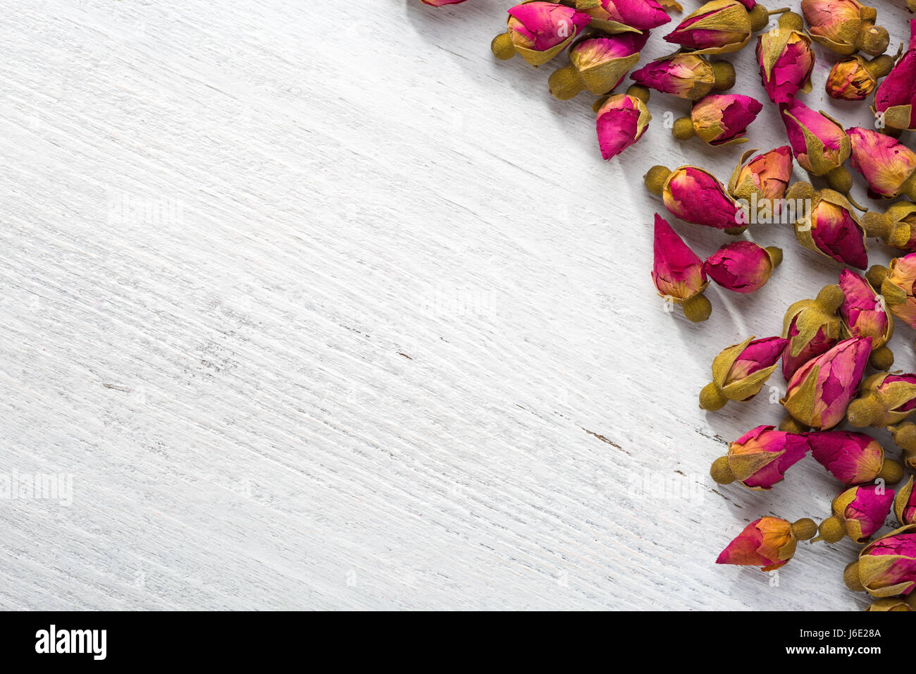 Dried buds of a tea rose on a  shabby wooden table. flat lay Stock Photo
