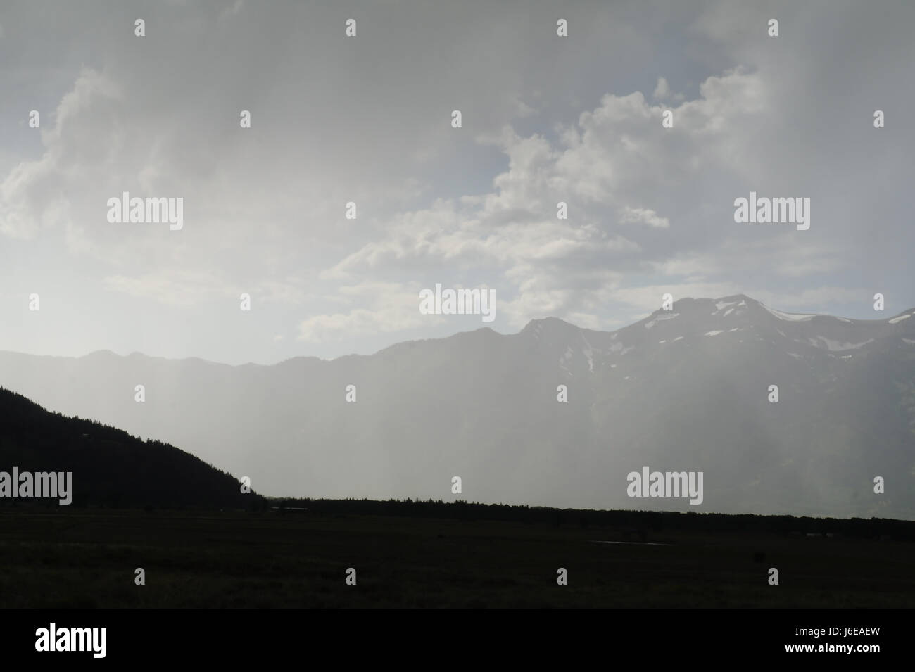 View through rain shower to South Teton peaks and silhouette West Gros Ventre Butte from Grand teton National Park Entrance Turnout, Wyoming, USA Stock Photo
