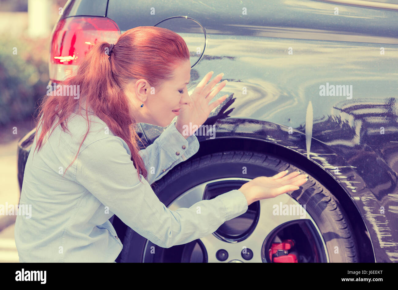 Frustrated young woman checking pointing at car scratches and dents outdoors outside Stock Photo