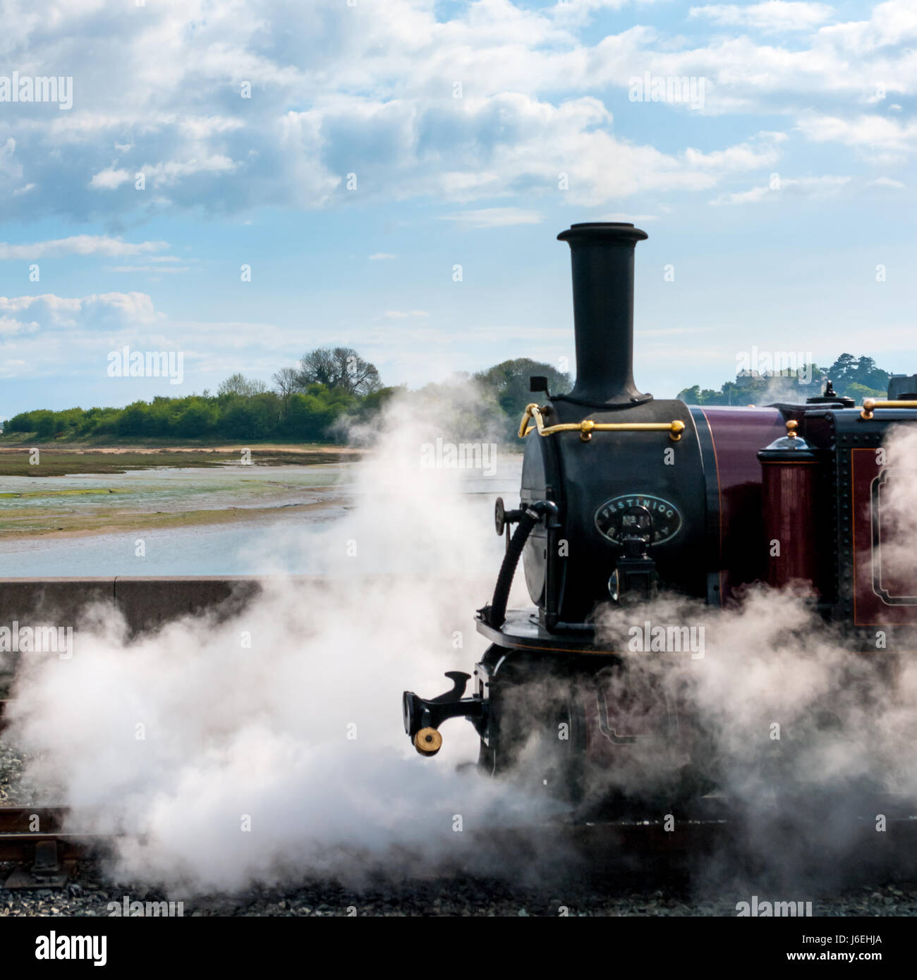 Engine in steam on sunny day with fluffy clouds. Boiler section. Stock Photo