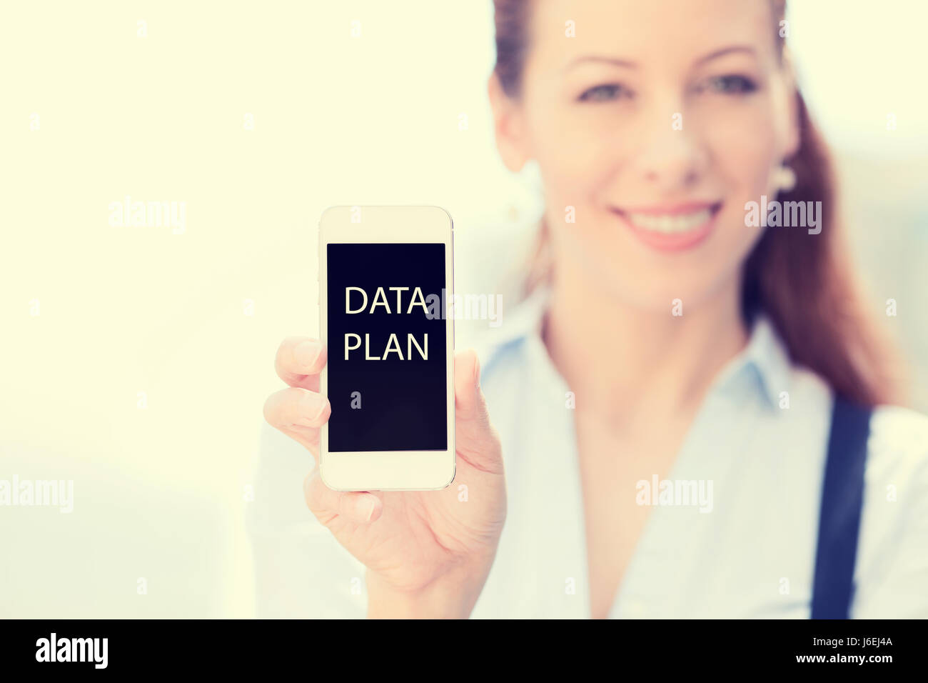 Smiling female showing mobile smart phone, data plan on screen isolated ...