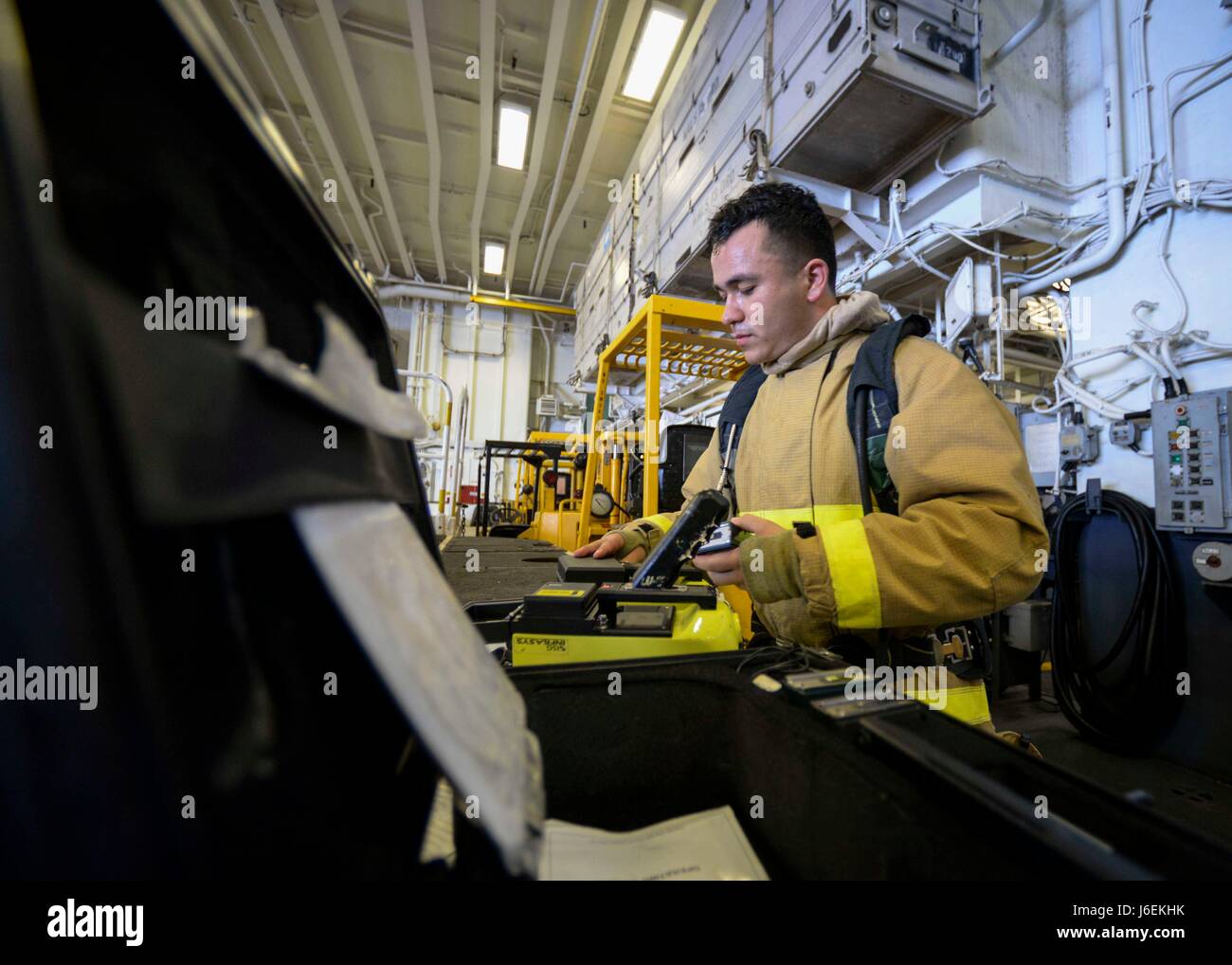 A Damage Controlman 3rd Class replaces batteries in a naval ...