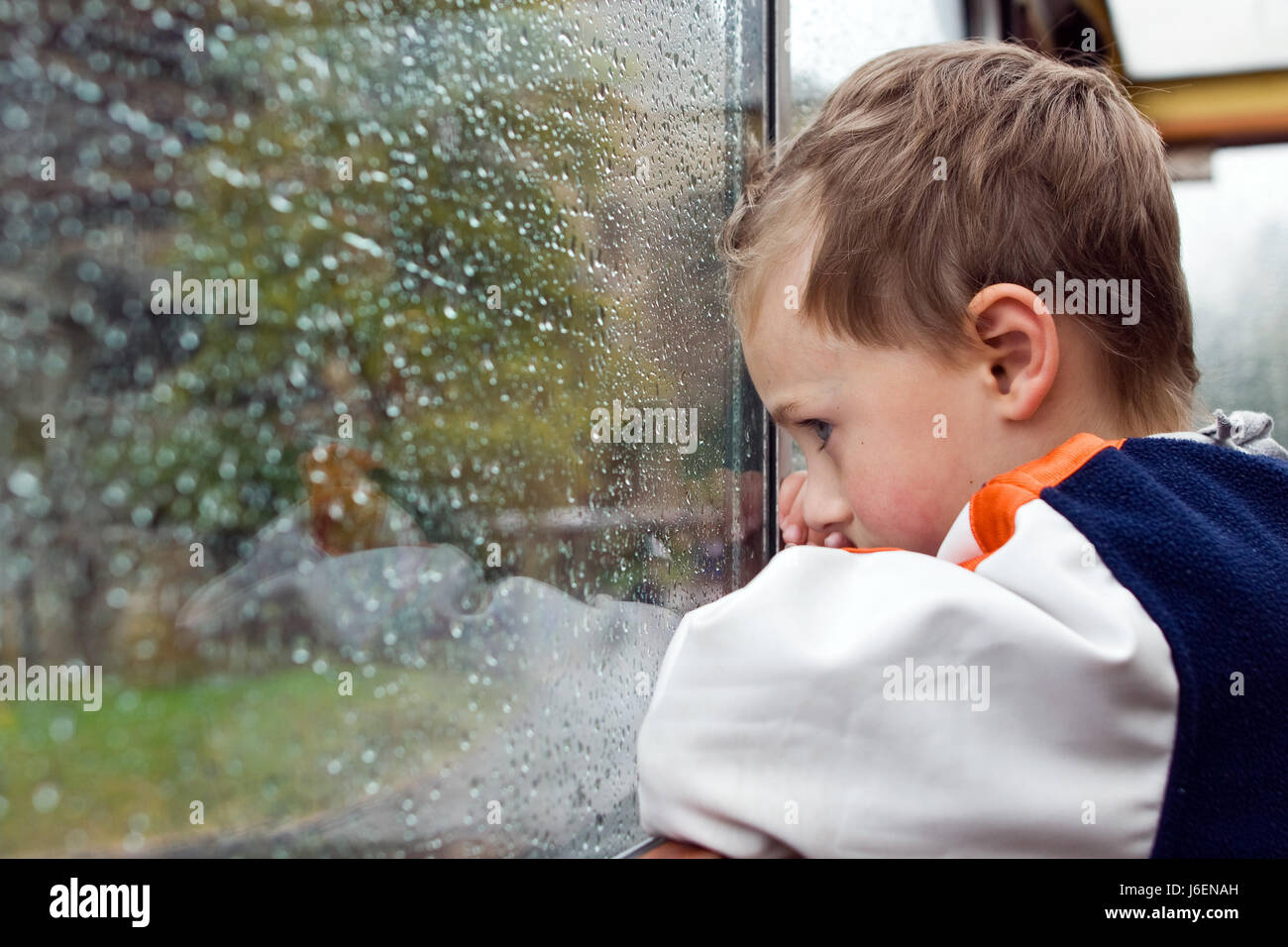 wait waiting window porthole dormer window pane sad young younger child weather Stock Photo