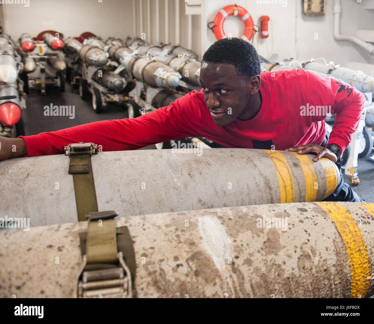 170509-N-RZ514-047  ARABIAN GULF (May 9, 2017) Aviation Ordnanceman 3rd Class Adarryl Chaney moves ordnance in the hangar bay of the aircraft carrier USS George H.W. Bush (CVN 77). The ship is deployed to the U.S. 5th Fleet area of operations in support of maritime security operations designed to reassure allies and partners, and preserve the freedom of navigation and the free flow of commerce in the region. (U.S. Navy photo by Mass Communication Specialist Seaman Jennifer M. Kirkman/Released) Stock Photo